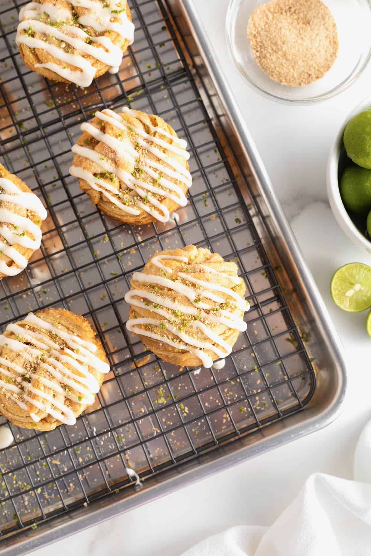 An aluminum baking pan with a wire cooling rack on top holding 4 key lime cruffins.