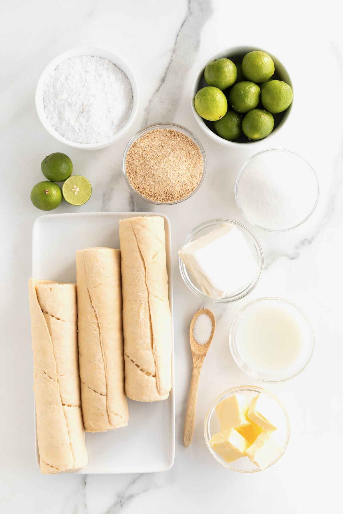 Ingredients to make key lime cruffins in small glass containers on a whit marble counter.
