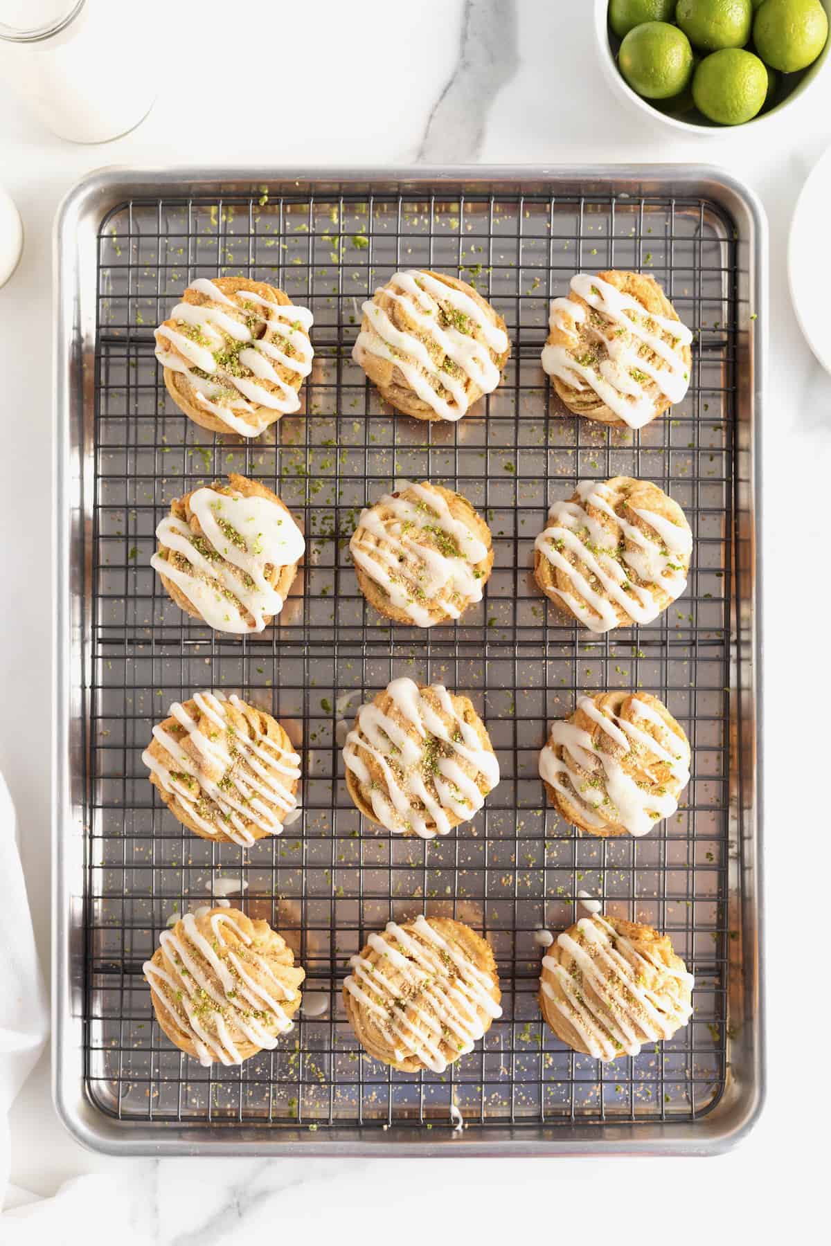 An aluminum baking pan with a wire cooling rack on top holding 12 key lime cruffins.