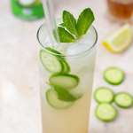 tall glass with coconut mocktail garnished with mint and cucumbers