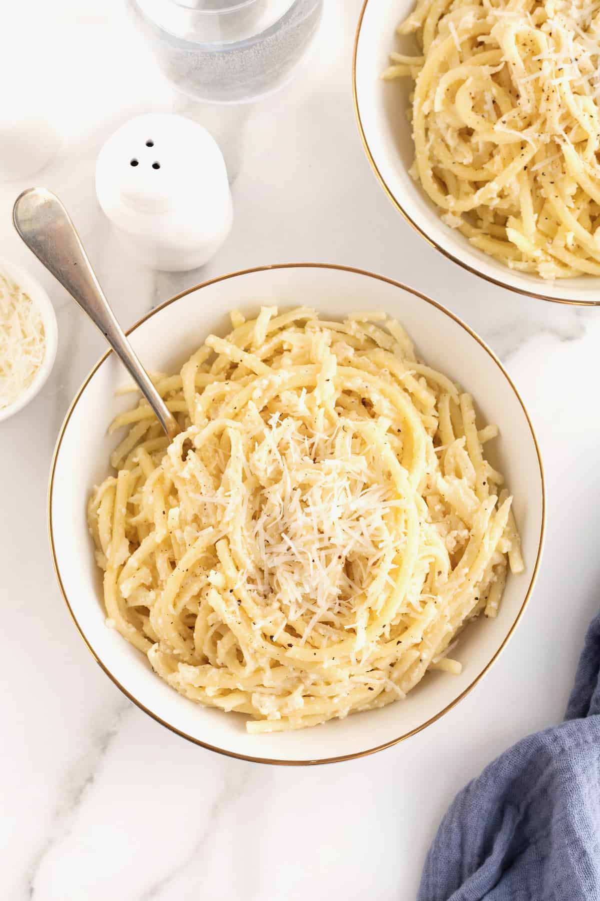 A large white, gold-rimmed serving bowl of cacio e Pepe.