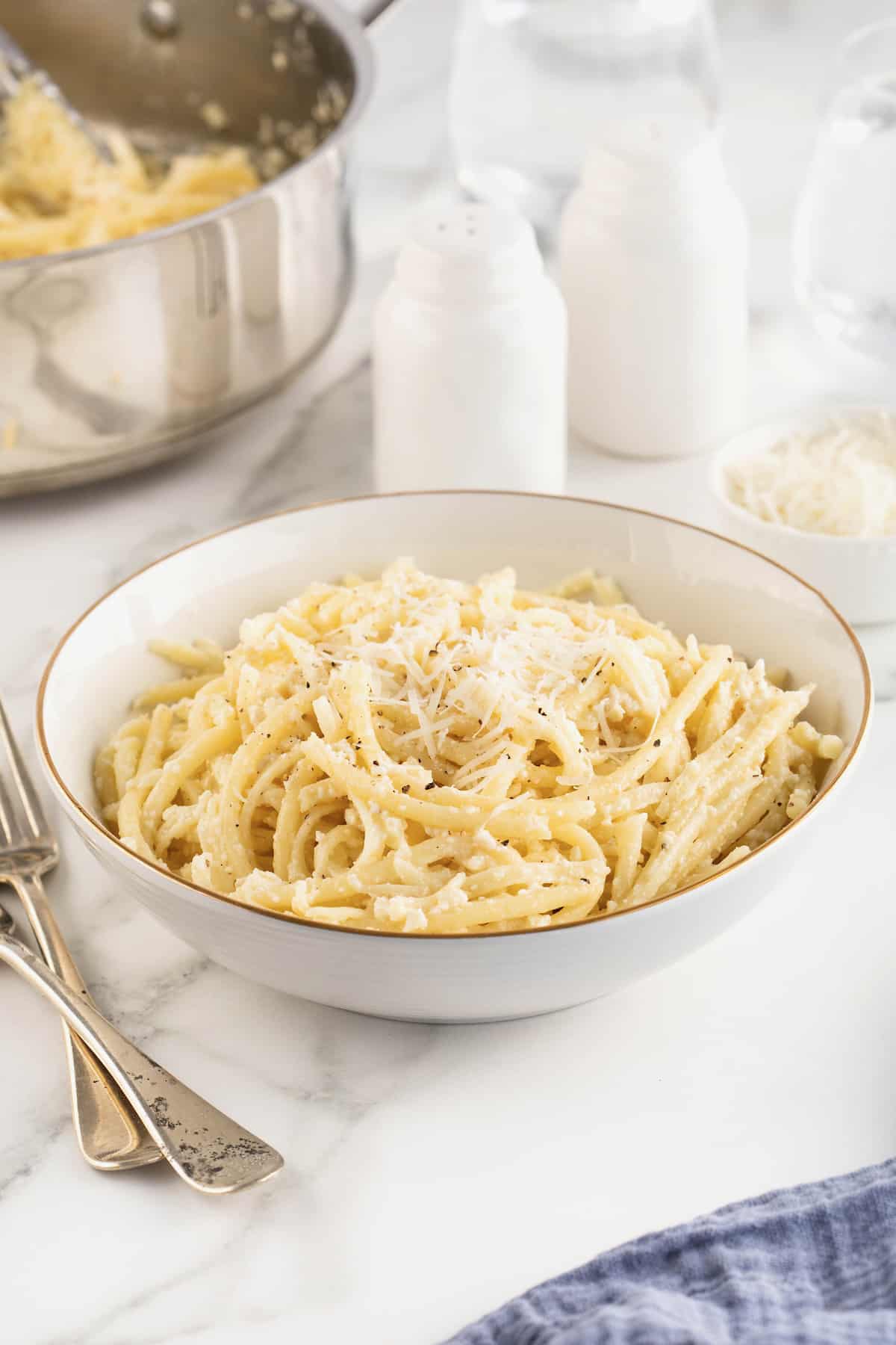 A large white, gold-rimmed serving bowl of Cacio e Pepe.