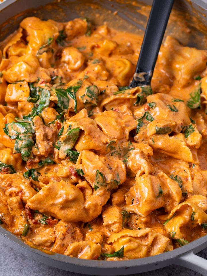marry me chicken tortellini skillet with a large black spoon