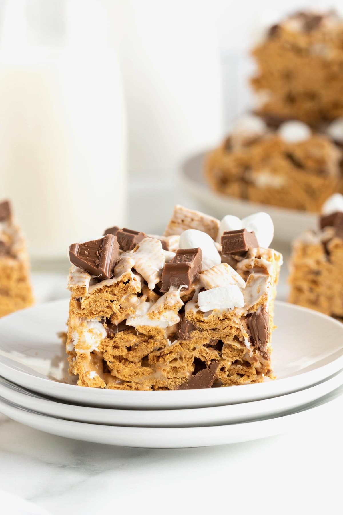 A no-bake s'mores bar on a stack of three white dessert plates.