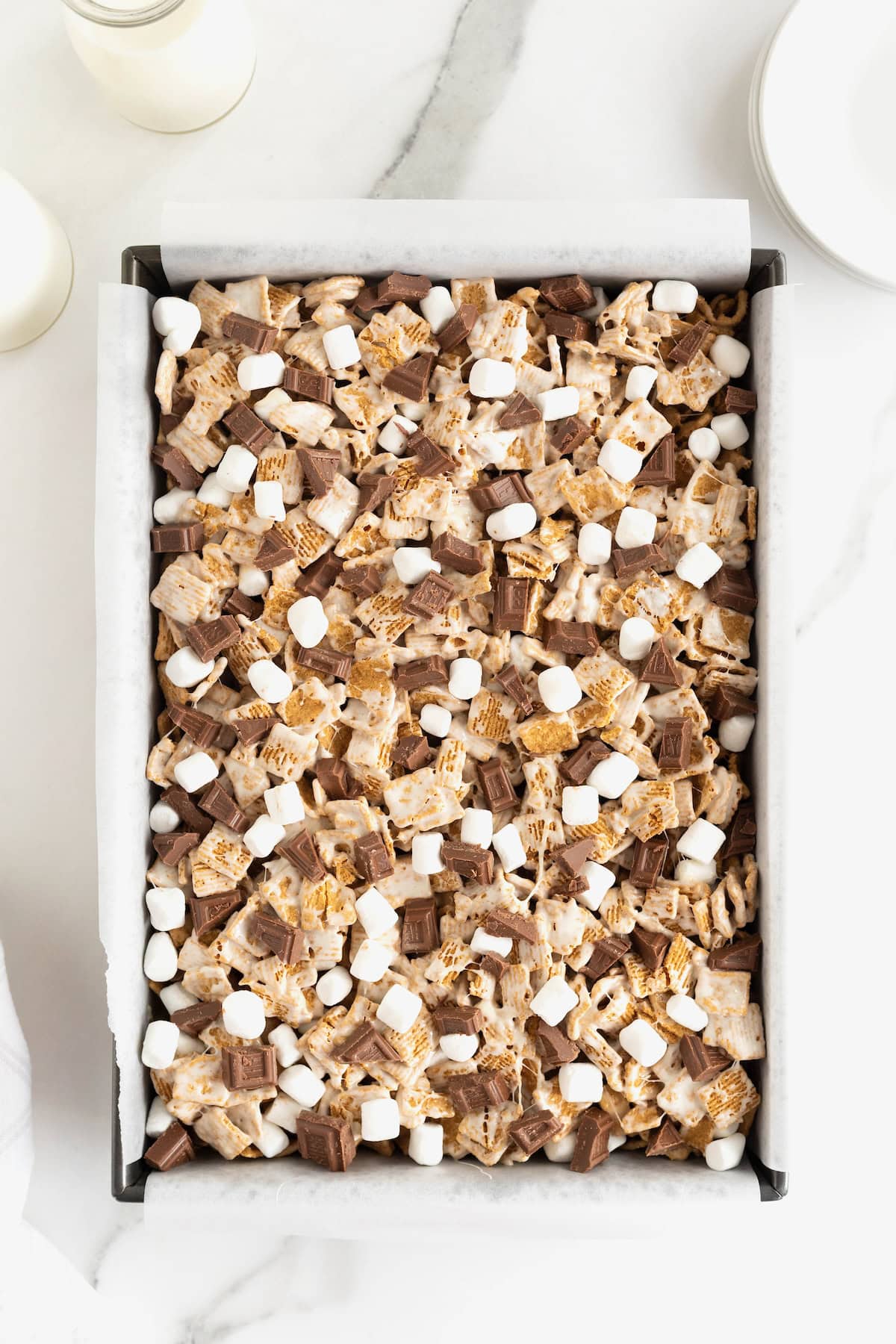 A parchment-lined baking pan of no-bake s'mores treats.