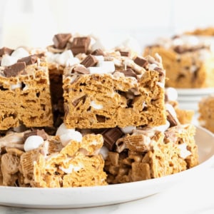 A large white rimmed plate stacked with S'mores no-bake treats.